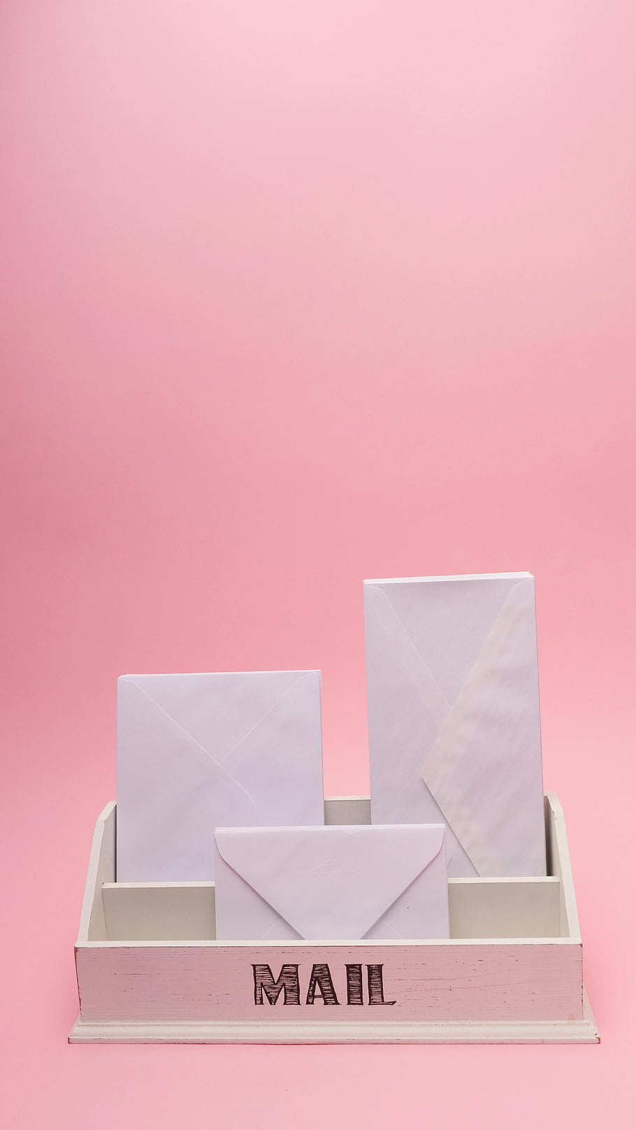 Bílé obálky, Minimalistická poštovní schránka, růžové pozadí, jednoduchý design, elegantní styl, Organizace pošty, Úložiště obálky, stolní příslušenství, kancelářská výzdoba, pastelové barvy, čistá estetika