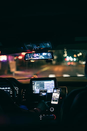 car interior, GPS navigation, smartphone, city lights, night driving, street view, dashboard display, rearview mirror, vehicle interior, urban night scene, navigation app