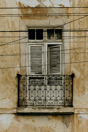 old balcony, weathered shutters, vintage architecture, Aracati Brazil, abandoned balcony, architectural details, rustic charm, historic building, window shutters, wrought iron railing, aged facade