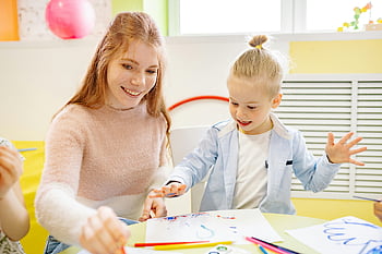 Ragazza che impara a dipingere, assistenza per l'insegnante, Attività di pittura, Aula luminosa, coinvolgimento dei bambini, insegnante sorridente, ambiente educativo, educazione artistica, impostazione in classe, Apprendimento creativo, Interazione insegnante-studente