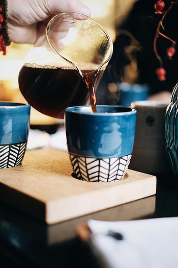 versare il caffè a mano, tazza di ceramica blu, atmosfera accogliente all'interno, caffè caldo, versare il caffè, tazza blu, vassoio di legno, impostazione interna, Tempo del caffè, momento del caffè, Atmosfera accogliente