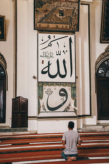 man praying, mosque, Islamic calligraphy, spiritual devotion, prayer, religious art, Islamic art, religious setting, mosque interior, prayer mat, devotion