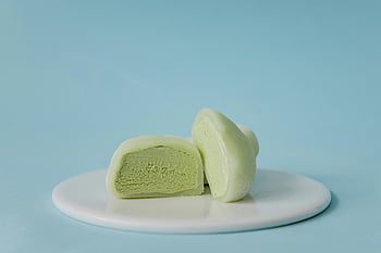 Nakrájené zelené mochi, zmrzlina, bílá keramická deska, Smetanový zelený čaj mochi, bílá deska, pastelově modré pozadí, Příchuť zeleného čaje, Mochi dezert, Japonský dezert, sladkost, fotografování potravin