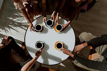 coffee drink, ceramic cups, table top, friends enjoying, café table, warm setting, group gathering, coffee time, social moment, cozy atmosphere, overhead view