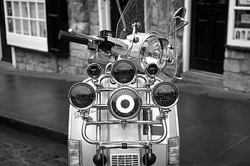 grayscale photo, scooter motorcycle, vintage Vespa, city street, black and white, nostalgia, urban scene, classic scooter, retro style, street photography, vintage transport