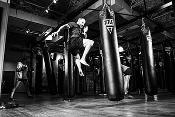 man kicking, heavy bag, gym training, punching bags, action scene, fitness workout, boxing gym, athletic man, sports training, indoor gym, exercise equipment