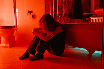 woman crying, bathroom, red lighting, loneliness, introspection, emotional scene, solitary figure, emotional photography, red ambiance, bathroom setting, emotional expression