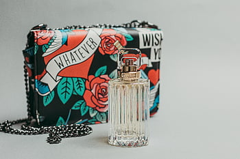 Cartier perfume bottle, colorful designer bag, flatlay setting, stylish accessories, glass bottle, designer handbag, chic arrangement, luxury items, fashion photography, flat lay composition, perfume and bag