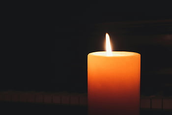 lighted pillar candle, glowing candle, close-up candle, dark background, warmth, serenity, candlelight, flame, ambiance, cozy, illumination