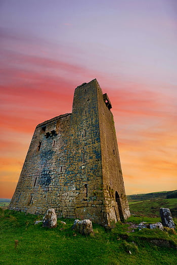 Medieval stone tower, Irish landscape, vibrant sunset, County Galway, scenic view, green grass, historic structure, ancient ruins, rural scene, sunset colors, stone architecture