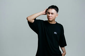 Mann, Schwarzes Crew-Nacken-T-Shirt, Studioportrait, junger Mann, verwirrter Ausdruck, grauer Hintergrund, Freizeitkleidung, Innenfotografie, männliches Model, kurzes Haar, schwarzes T-Shirt