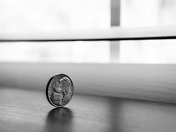 monochrome photography, round silver coin, close-up, standing coin, smooth surface, black and white, coin reflection, minimalistic, still life, coin art, monochrome art