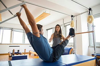 Muž s protetickou nohou, rehabilitace, Cvičení pilates, vedení trenéra, tělocvična, fyzikální terapie, Protetická noha, cvičební zařízení, zdatnost, rehabilitační centrum, Školení