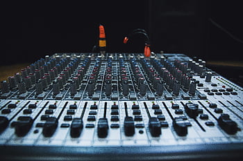 Gray audio mixer, audio mixing console, faders, knobs, studio lighting, close-up, audio equipment, sound mixing, music production, recording studio, audio controls