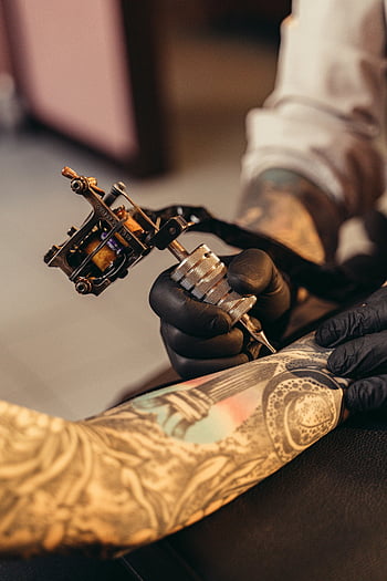 tattoo machine, client's arm, tattooed arm, studio setting, detailed view, tattoo artist, tattoo process, skin art, body modification, professional tattoo, tattoo studio