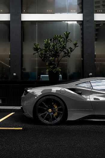 grauer Sportwagen, geparktes Auto, nasse Stadtstraße, Modernes Glasgebäude, Luxus-Sportwagen, elegantes Design, städtischen Umfeld, Autofotografie, ferrari, nasser Belag, Stadtbild im Hintergrund