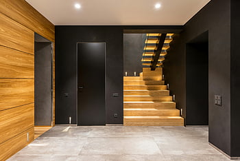 modern corridor, wooden staircase, sleek design, warm interior, inviting space, modern interior, black walls, tiled floor, contemporary design, indoor lighting, spacious hallway
