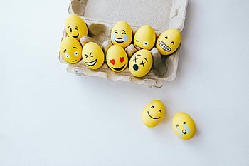 yellow painted eggs, emoji faces, colorful Easter eggs, creative holiday touch, fun Easter decoration, yellow Easter eggs, emoji decorated eggs, Easter egg carton, festive Easter eggs, creative Easter eggs, emoji eggs