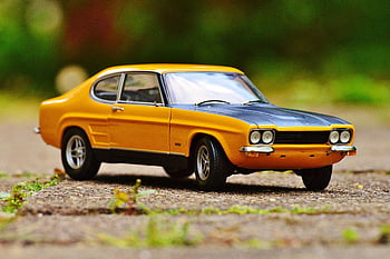 Ford Capri, miniature model, yellow and black, muscle car, tilt shift photography, vibrant colors, outdoor surface, detailed miniature, classic car, toy car, model car