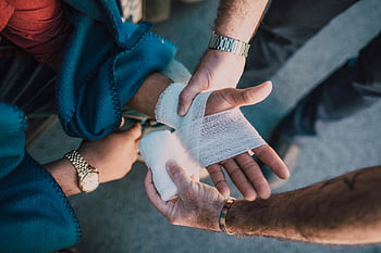 first aid, bandage, injured hand, outdoor care, close-up, two people, medical assistance, emergency care, outdoor first aid, bandaging hand, outdoor injury care