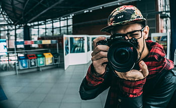 muž drží DSLR kameru, Mladý dospělý fotograf, fotografování v interiéru, moderní fotografie, dslr fotoaparát, Fotograf uvnitř, fotografické vybavení, příležitostný fotograf, městské fotografie, fotografování hobby, Foto nadšenec