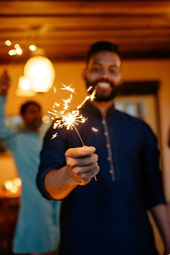 man holding sparkler, festive indoor celebration, warm atmosphere, joyful moment, bright sparkler, close-up photo, indoor celebration, sparkler celebration, festive atmosphere, man with sparkler, indoor sparkler