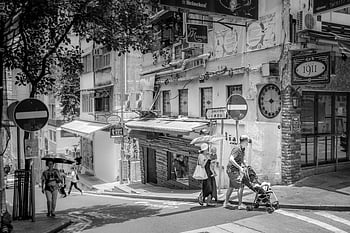 grayscale photo, people walking, Hong Kong, monochrome street view, urban architecture, black and white, cityscape, street scene, pedestrians, stroller, umbrellas