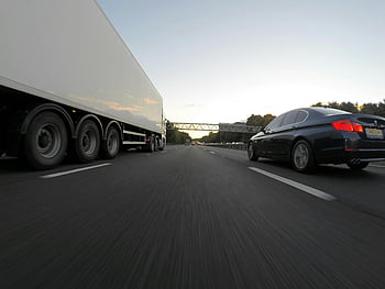 Blue Infiniti Sedan, White Freight Truck, highway, transportation dynamics, clear sky, cars and truck, speeding, road, vehicles, travel, motion
