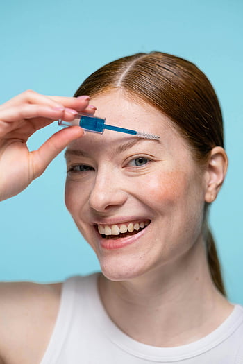 lächelnde Frau, Augenbrauen-Make-up auftragen, Augenbrauengel, Schönheitsroutine, Hautpflege, Kosmetika, fröhliche Frau, Make-up-Anwendung, Schönheitsprodukte, Gesichtspflege, Hautpflege-Routine