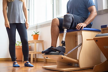 picior protetic, Exercițiu de reabilitare, Setare de sală, ședința omului, antrenor, fizioterapie, Reabilitare protetică, echipament de exerciții fizice, Sala de sport interioară, proces de recuperare, utilizator protetic