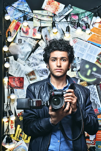 رجل يحمل الكاميرا،  كاميرا dslr سوداء،  مصور فوتوغرافي،  إضاءة الخلفية الفنية،  إضاءة الاستوديو،  شعر مجعد،  سترة جلدية،  الخلفية الإبداعية،  التصوير،  صورة،  تصوير داخلي