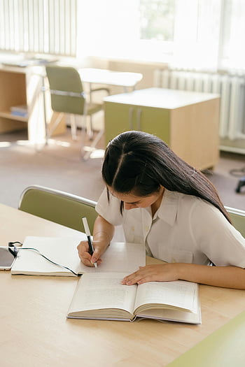 Frau studieren, Bibliothek, junge Frau, Notizbuch schreiben, Tisch studieren, Bibliothekstisch, Buch, Stift, fokussierter Schüler, akademisches Umfeld, Lernen
