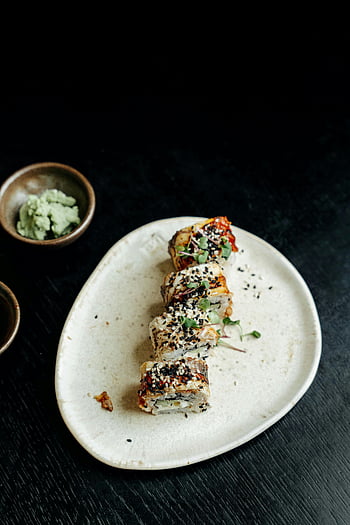 sushi rolls, wasabi, sesame seeds, ceramic plate, close-up, garnished, Japanese food, sushi dish, food photography, dining, sushi presentation