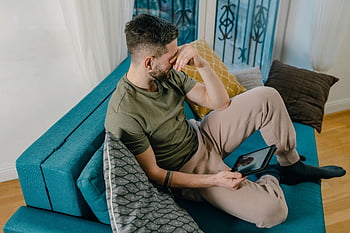 رجل يبكي،  أريكة زرقاء،  رجل متوتر،  عقد الكمبيوتر اللوحي،  غرفة معيشة مريحة،  رجل جالس،  لحظة عاطفية،  المشهد الداخلي،  ملابس غير رسمية،  إعداد المنزل،  وضعية مريحة