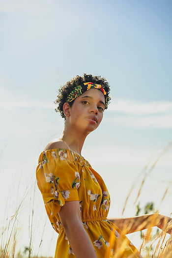 Frau im Feld, Gelbes Blumenkleid, sonniges Feld, Porträt der Frau, Porträt im Freien, natürliches Licht, Stirnband, Lockige haare, Sommermode, Feldfotografie, schöne Frau