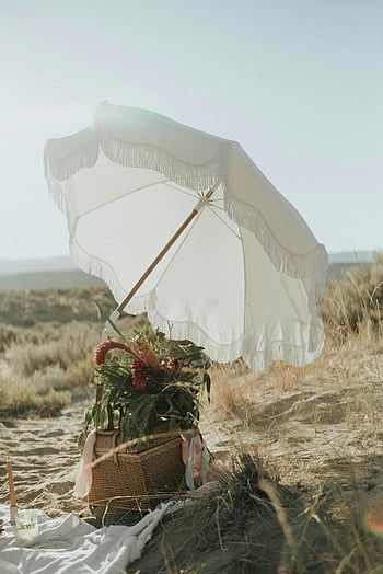 παραλιακό πικνίκ, λευκή ομπρέλα, πικνίκ Boho, αμμώδη ακτή, καλάθι με λουλούδια, γαλήνια παραλία, ηλιόλουστη ομπρέλα, παραλία, boho style, παραλία λουλούδια, ΚΑΛΑΘΙ πικ-νικ