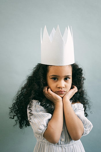 Roztomilá černá dívka, Outfit princezny, foto studio, rozkošná dívka, kudrnaté vlasy, papírové korunky, zamyšlený výraz, Mladá princezna, studiový portrét, fotografování dětí, Hravý kostým
