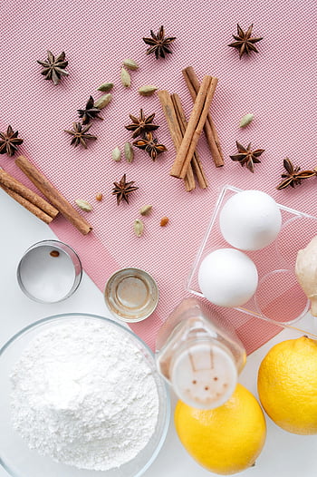 pie ingredients, pink surface, cinnamon, eggs, lemons, flat lay, baking ingredients, star anise, flour, sugar