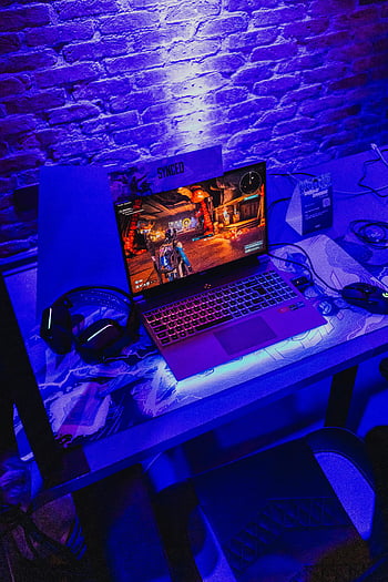 modern gaming laptop, headphones, mouse, desk, purple neon lighting, gaming setup, laptop gaming, headphones on desk, mouse pad, gaming accessories, brick wall background