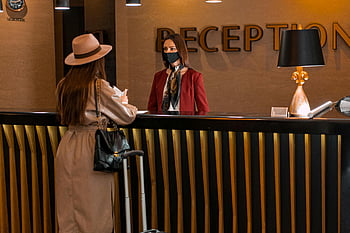 お互いを見ている女性、 ホテルの受付、 マスクを着た受付係、 女性が話している、 ホテルロビー、 フェイスマスク、 顧客サービス、 旅行、 荷物、 プロの服装、 おもてなし