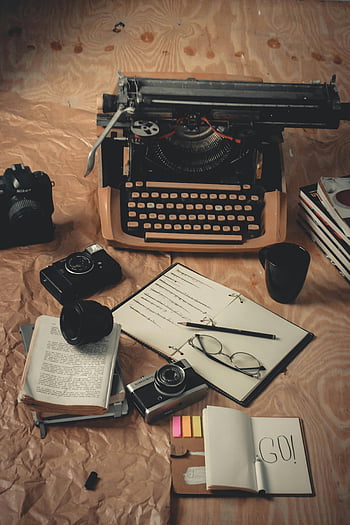 vintage írógép, kamerák, könyvek, Íróeszközök, fa felület, nosztalgikus jelenet, fekete és ezüst kamera, fehér nyomtató papír, nyitott notebook, szemüveg, ceruzák