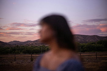 blurry portrait, woman, San Diego sunset, hills, vibrant sky, scenic background, outdoor photo, evening light, natural landscape, soft focus, female figure