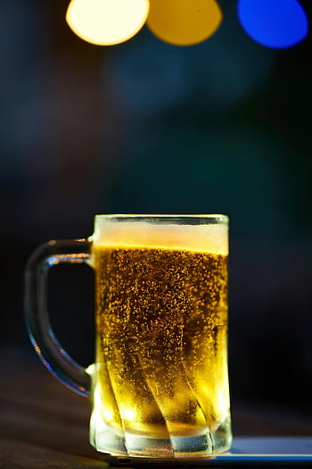 glass mug, yellow liquid, cold beer, frothy head, bokeh lighting, dim setting, beer mug, glass beer mug, yellow beer, frothy beer, bokeh effect