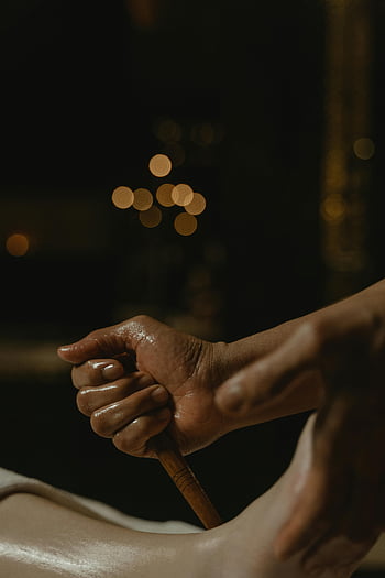 기름을 바른 손, 나무 스틱, 발 마사지, 자세한 견해, 마사지 처리, 막대기를 잡고 있는 손, 오일 마사지, 나무 마사지 도구, 마사지 요법, 이완 치료, 스파 트리트먼트