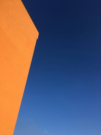 orange gebäude, blauer Himmel, Minimalistische Zusammensetzung, Auffallender Kontrast, lebendige Farben, Architekturfotografie, Outdoor-Szene, modernes Design, geometrische Formen, klarer Himmel, städtische Landschaft