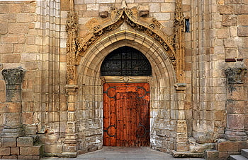 Gotické dveře kostela, kamenný oblouk, složitě vyřezávané, Zavřené hnědé dřevěné dveře, Podrobný pohled, gotická architektura, kamenné zdivo, Ozdobený design, náboženské budovy, historické struktury, středověké umění