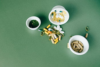 flat lay, alternative medicines, herbal pills, vitamin capsules, green surface, health supplements, natural remedies, wellness products, dietary supplements, flat lay photography, alternative health
