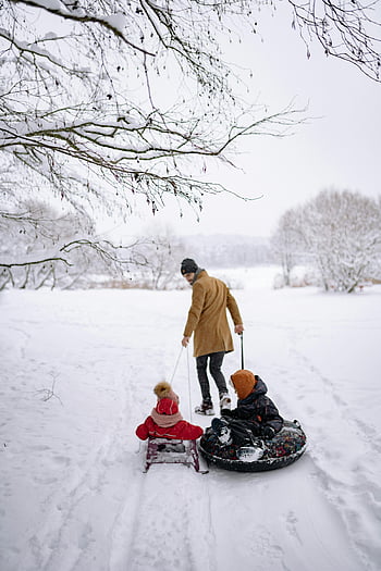 father pulling sleds, winter wonderland, joyful memories, snow tube, children on sleds, snowy landscape, family fun, outdoor winter activities, winter scenery, snowy day, winter recreation