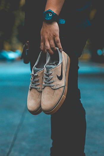 Nike tenisky, Beige tenisky, městské módy, venkovní styl, osoba drží boty, ležérní obuv, streetwear, moderní móda, životní styl fotografie, kultura tenisky, Nike Brand