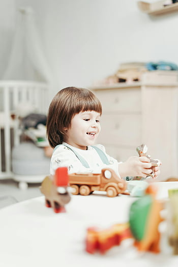 遊ぶ子供、 カラフルな木製のおもちゃ、 幸せな子、 屋内設定、 明るい部屋、 木製ブロック、 幼児のおもちゃ、 プレイタイム、 室内遊び、 子供のおもちゃ、 笑顔の子供